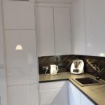 Biała kuchnia na wymiar w połysku z czarnym blatem i nowoczesnym wykończeniem 3