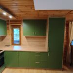 Zielona kuchnia na wymiar z drewnianymi elementami i nowoczesnym oświetleniem